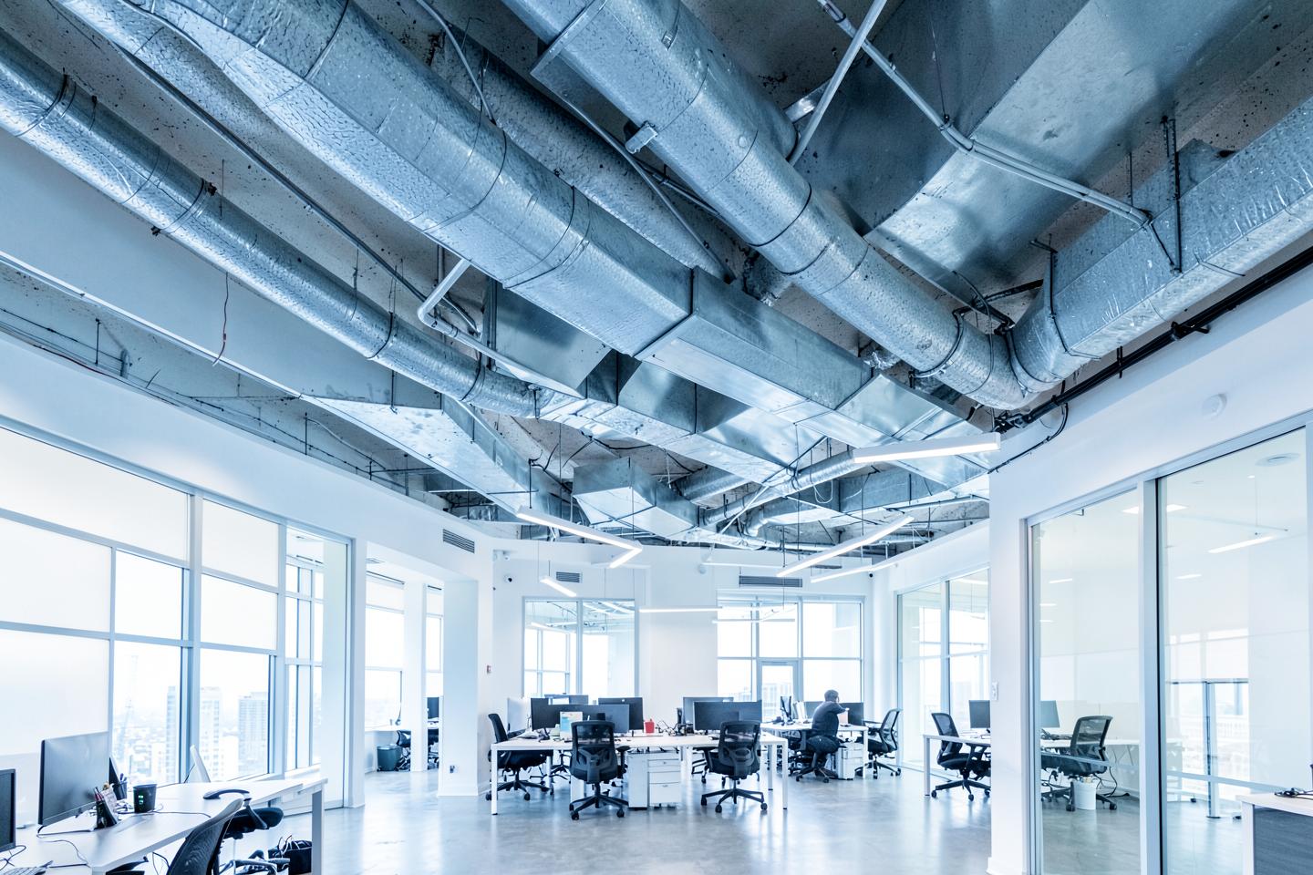 Exposed commercial HVAC ductwork above a modern open-plan office in Richmond, Virginia